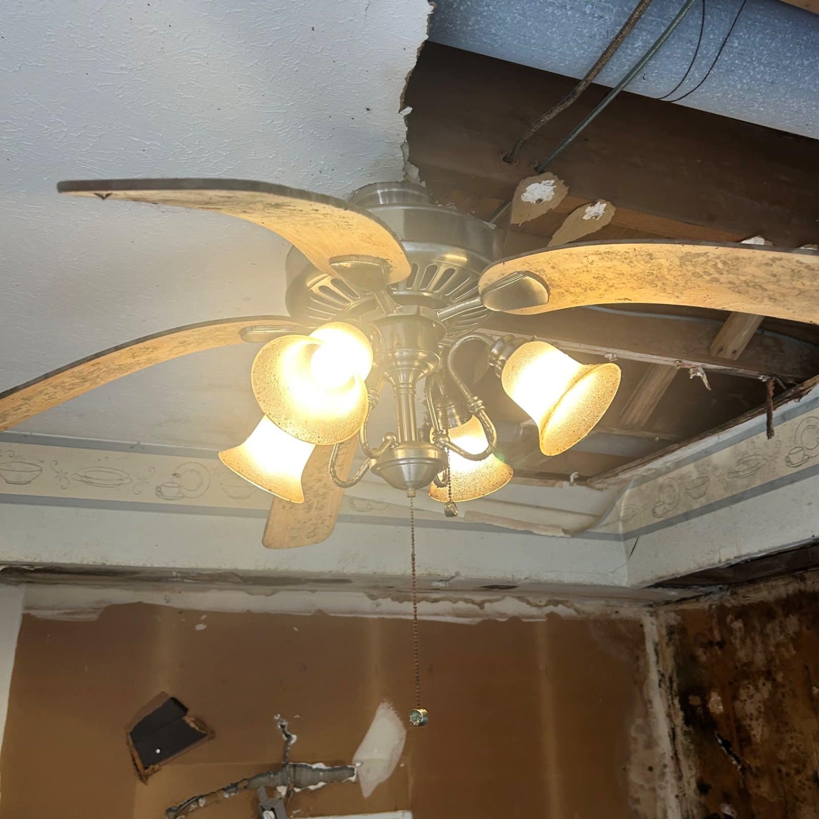 Water-damaged ceiling around fan fixture; visible staining and drywall deterioration indicate moisture intrusion